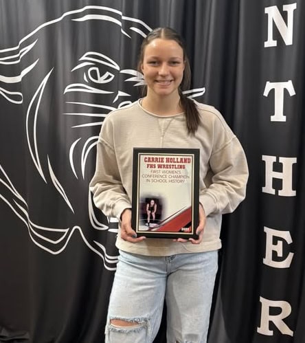 FHS athlete Carrie Holland holding her wrestling conference championship plaque.