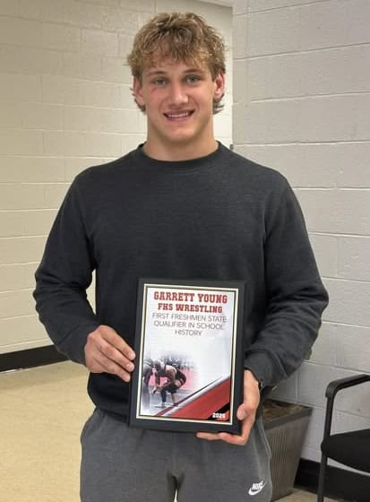FHS wrestler Garrett Young holding award for first freshman state qualifier in school history.