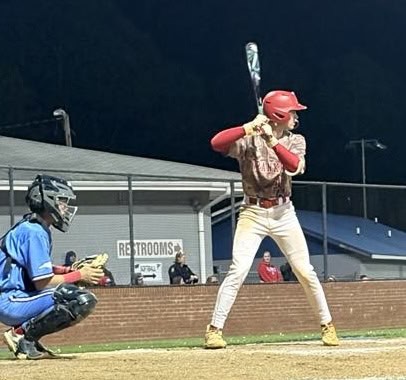 Young baseball player preparing to hit during a game at night.
