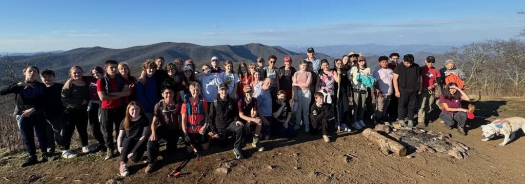 Group of students hiking on trail with scenic mountain views in the background.