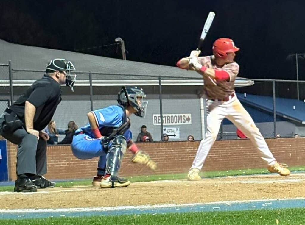 Young baseball player at bat during a game at night.
