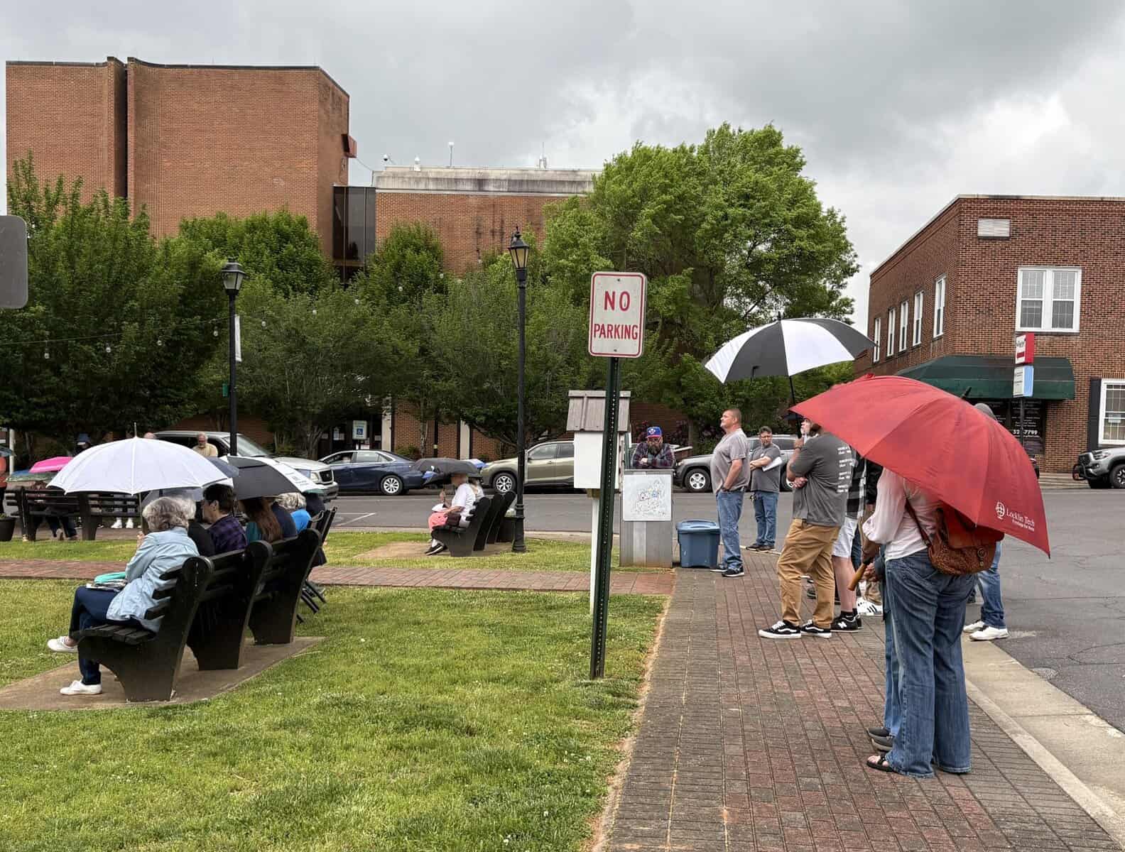 People holding umbrellas during outdoor prayer event in Macon, Georgia.