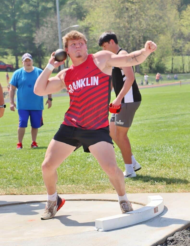 Young athlete throwing shot put during track and field event at Macon Sense meet.