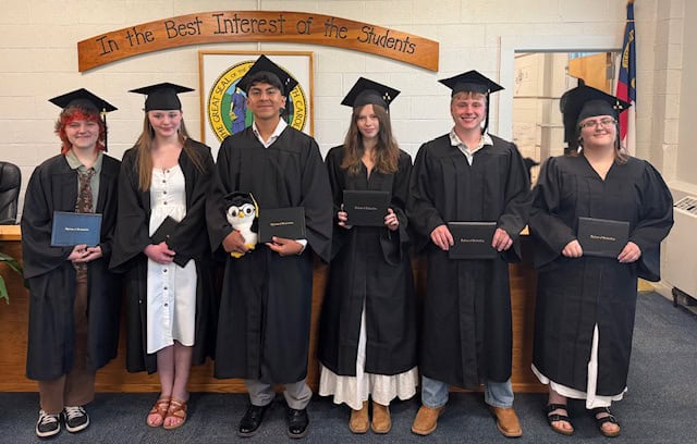 Group of diverse graduates in caps and gowns celebrating graduation.