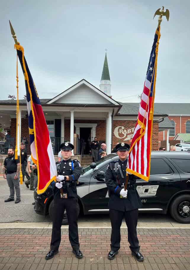 Officers holding flags during memorial event for fallen officers.