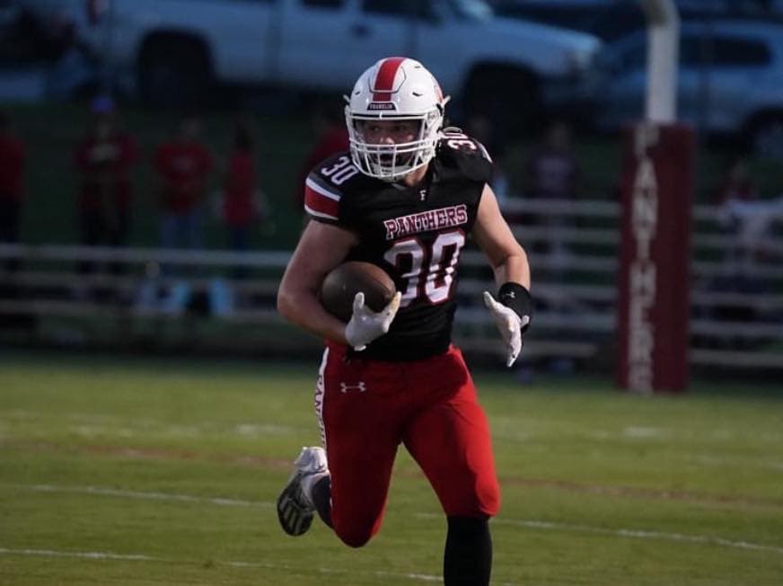 Football player running with ball during game.