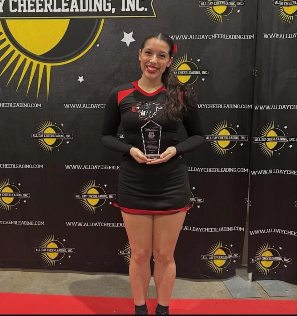 FHS cheerleader holding award at NCHSAA recognition event.