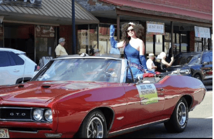 Woman riding in a vintage red convertible during Macon Sense event parade.