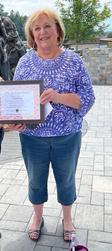 Woman holding award in front of native plant garden at park.