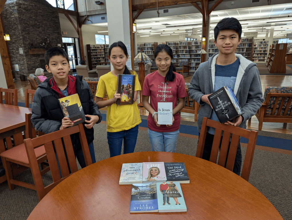 Young teens showcase their favorite books at a library donation event.