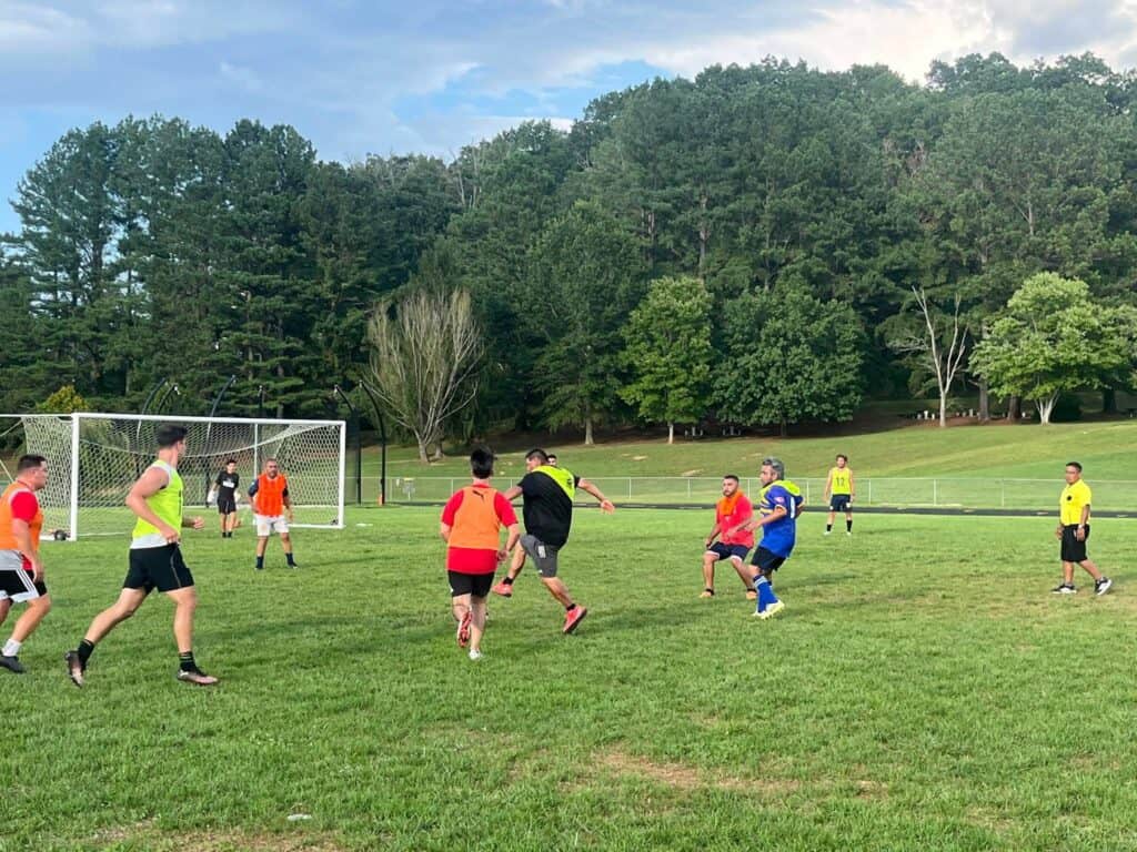 Youth soccer players practicing on a grassy field with coaches guiding skill improvement.