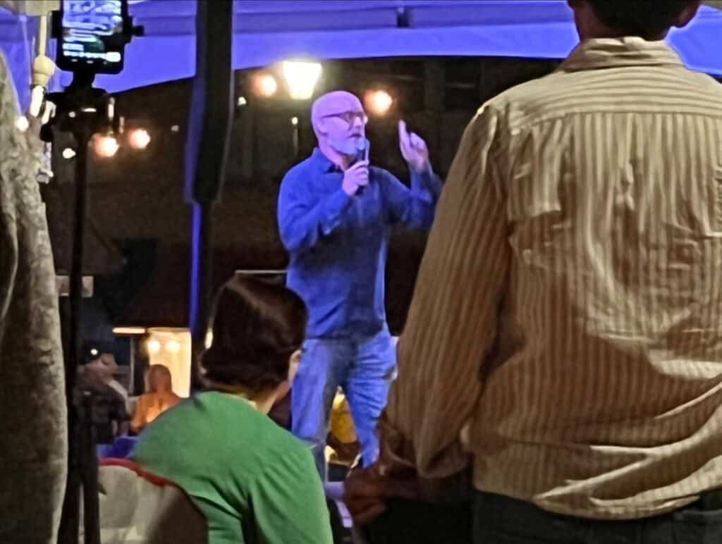 Man praying on stage during patriotic event in front of audience.