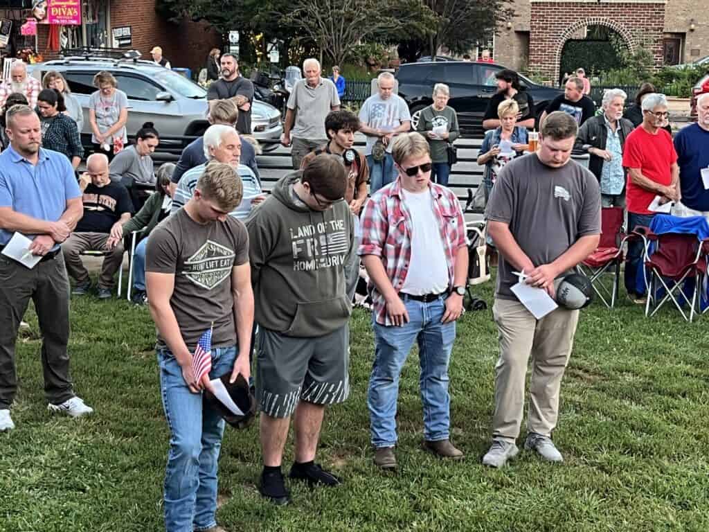 Group of people praying outdoors during a community event.