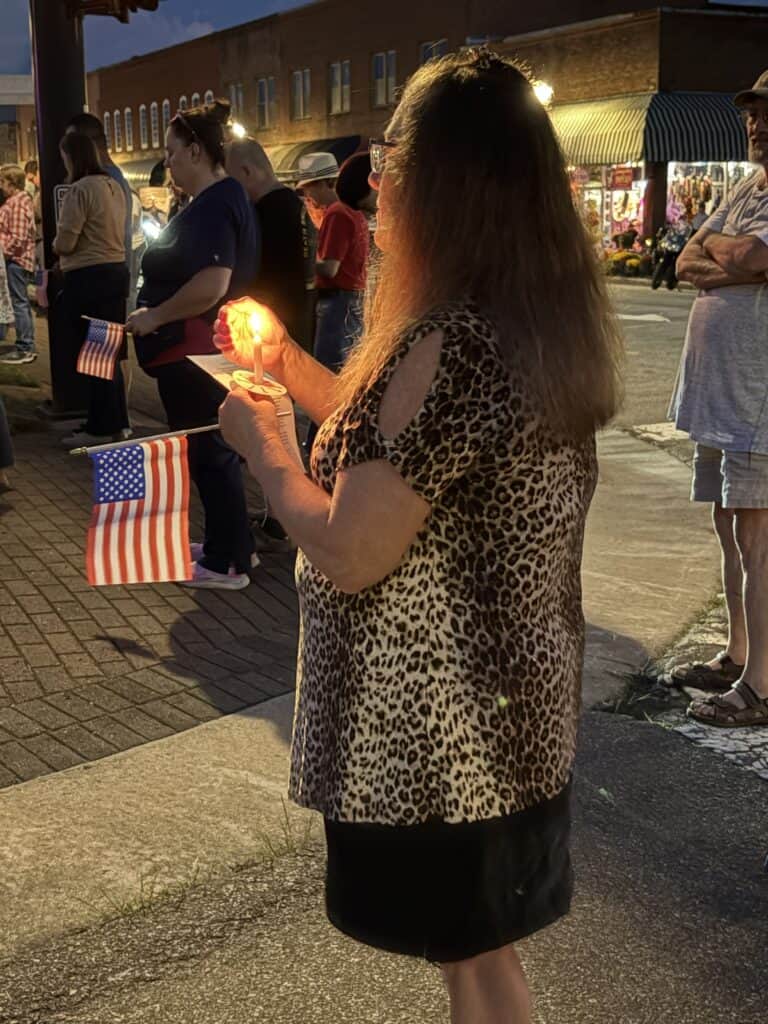 Woman praying with candle during patriotic event in downtown Macon, Georgia.