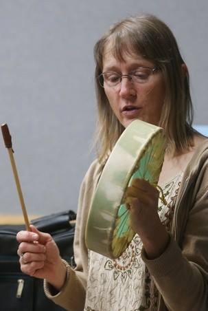 Woman playing a drum with a drumstick, showcasing artistic expression.