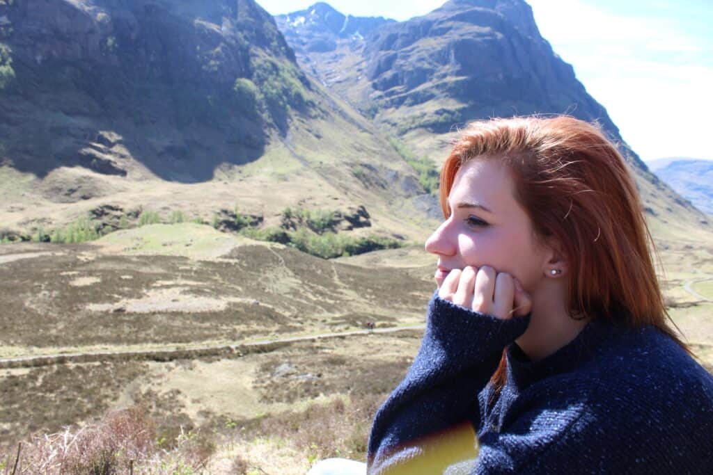 Young woman enjoying scenic mountain view at Scottish Tartan Museum.