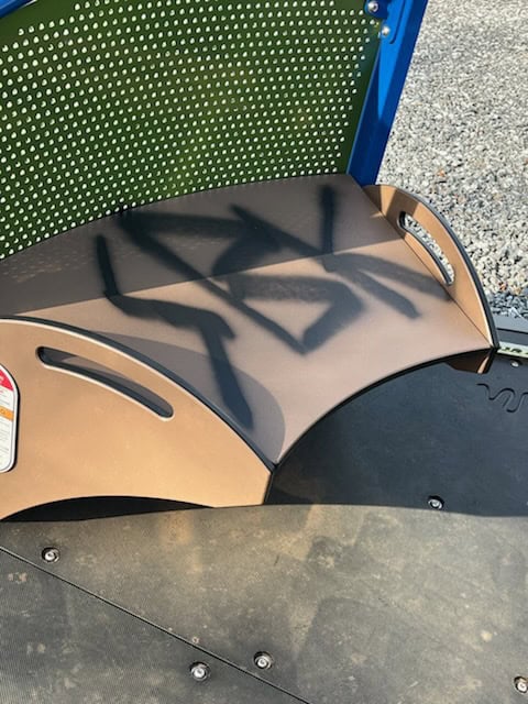 Vandalized playground equipment at Sunnyside play area, showing graffiti and damage.
