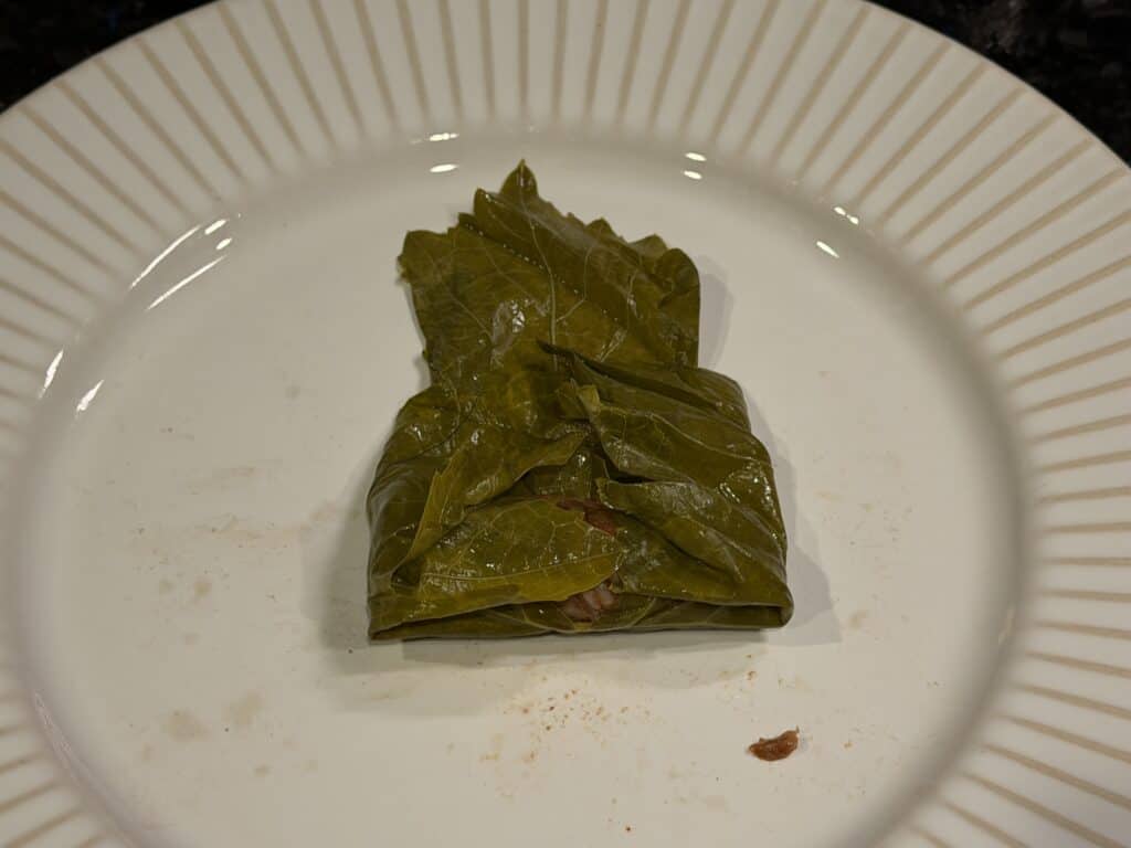 Traditional stuffed grape leaves served on a white plate.