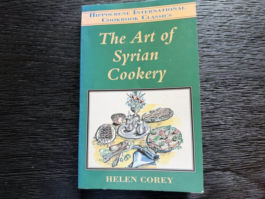 Syrian cookery book cover with traditional dishes and ingredients.