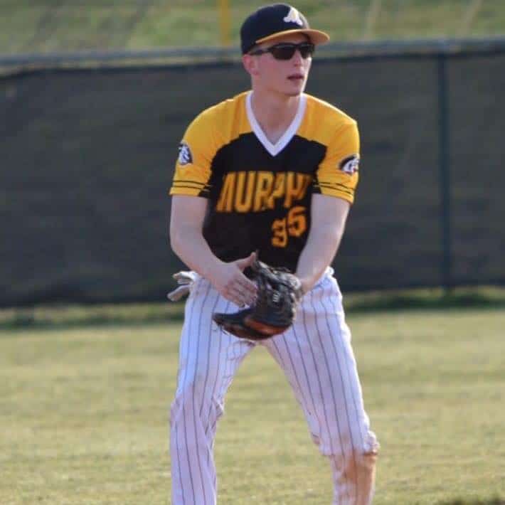 Young baseball player in yellow and black uniform ready to catch.