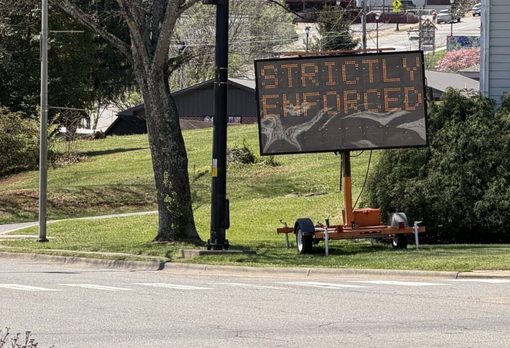 ENFORCED sign alerting drivers about strict traffic regulations in downtown area.