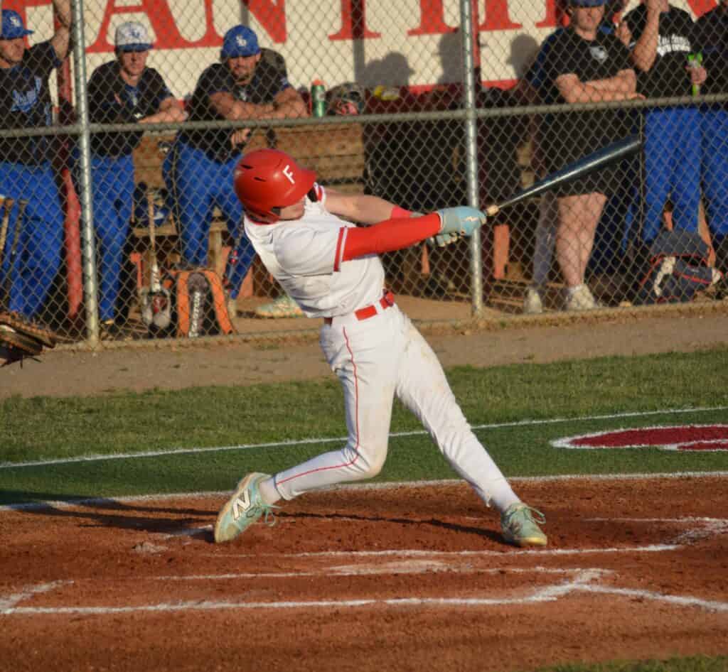 Young baseball player swinging at a pitch during a game.