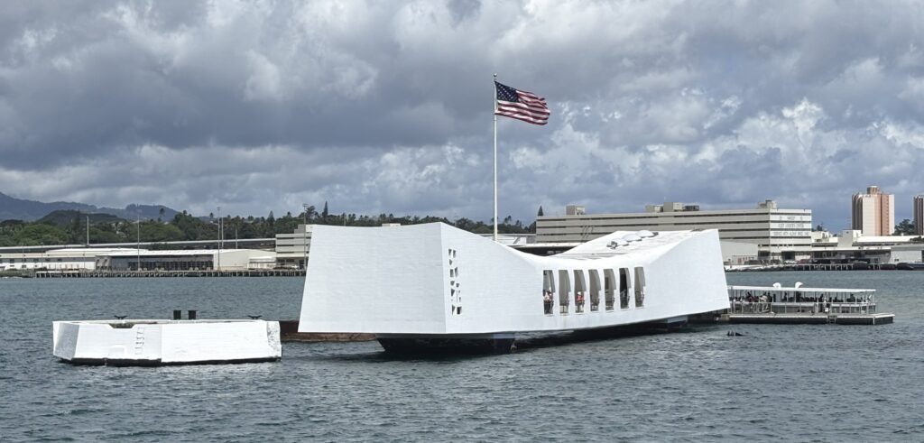 Modern waterfront building with unique architecture and American flag, located by the water.