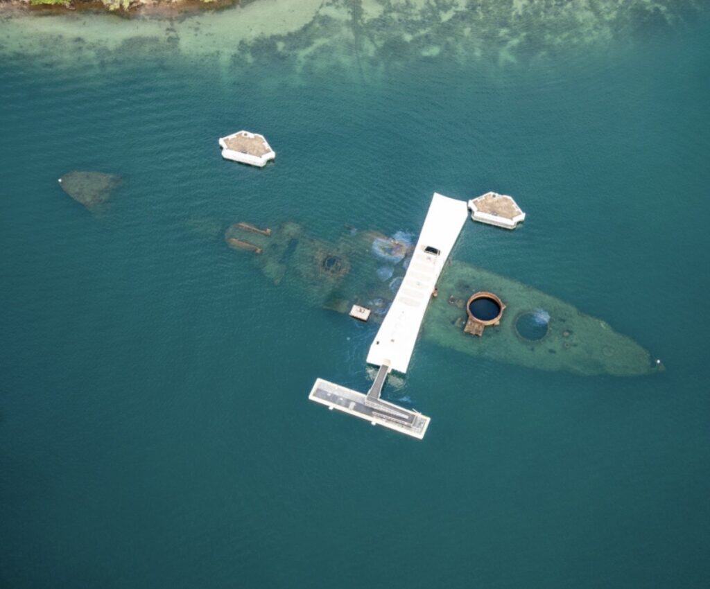 Aerial view of a sunken submarine with surrounding floating structures in a body of water.