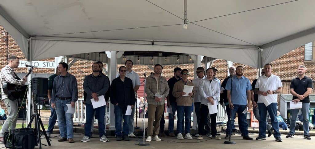 Group of local Christians singing and praying outdoors during a community prayer event.