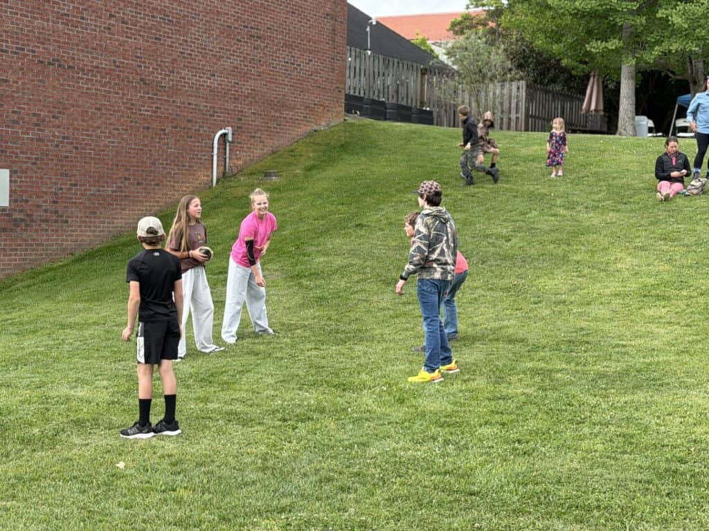 Children playing and socializing on a grassy hill in a community park.
