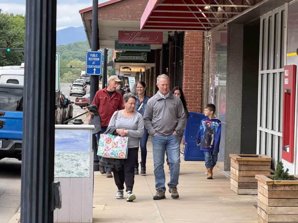 Group of people walking on downtown Macon street with shops and storefronts.
