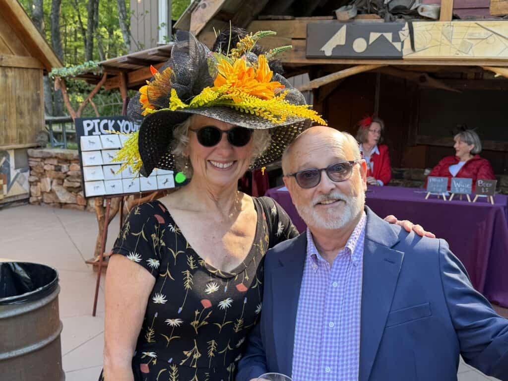 Elegant woman in a floral dress and large hat with sunflowers at Macon Sense event.
