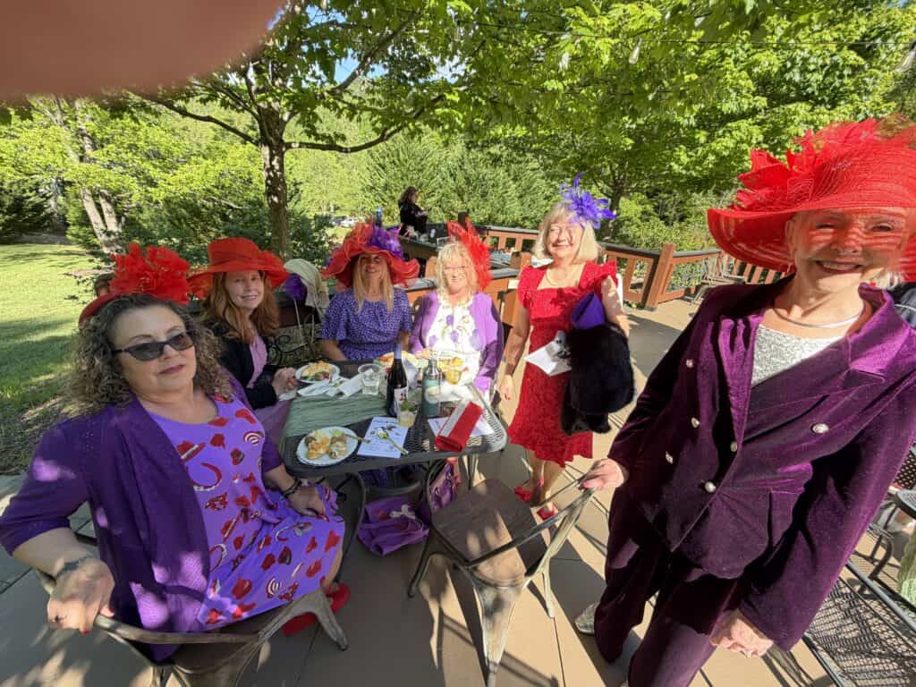 Women enjoying garden party in colorful hats and dresses.
