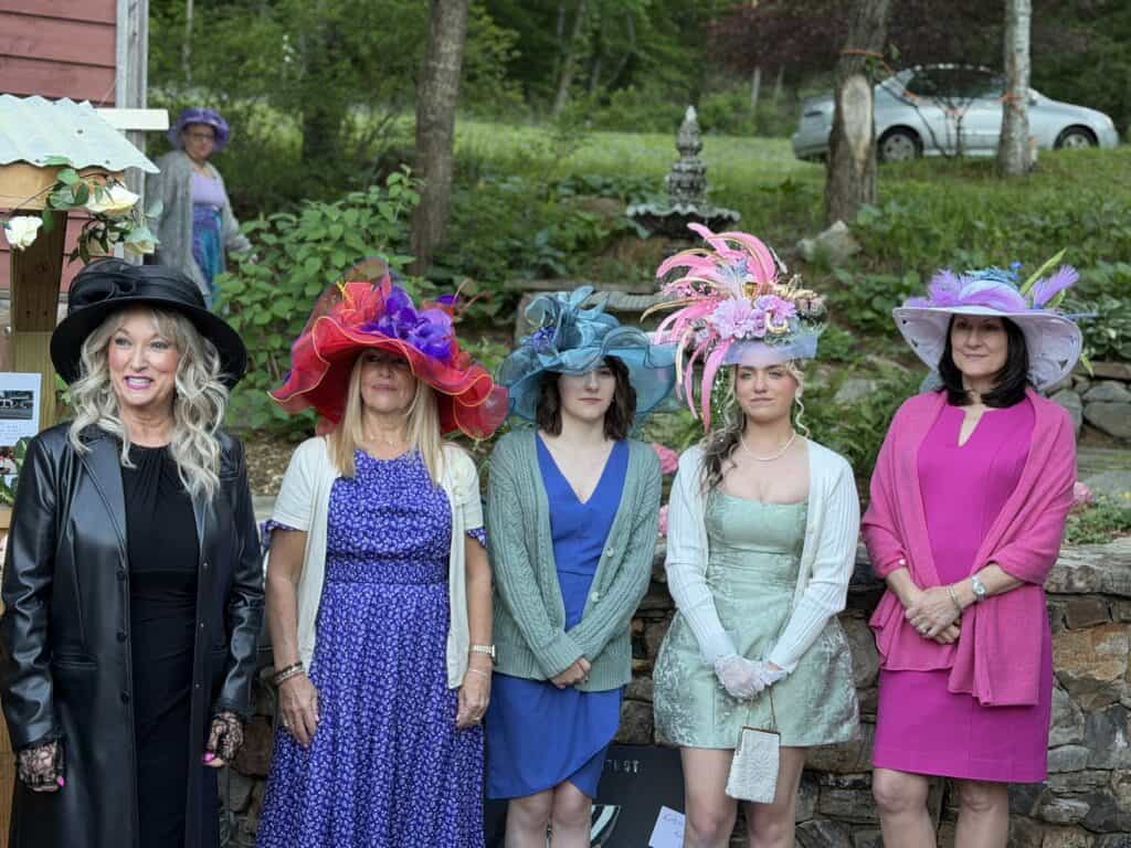 Elegant women wearing colorful, elaborate hats during a spring fashion event.