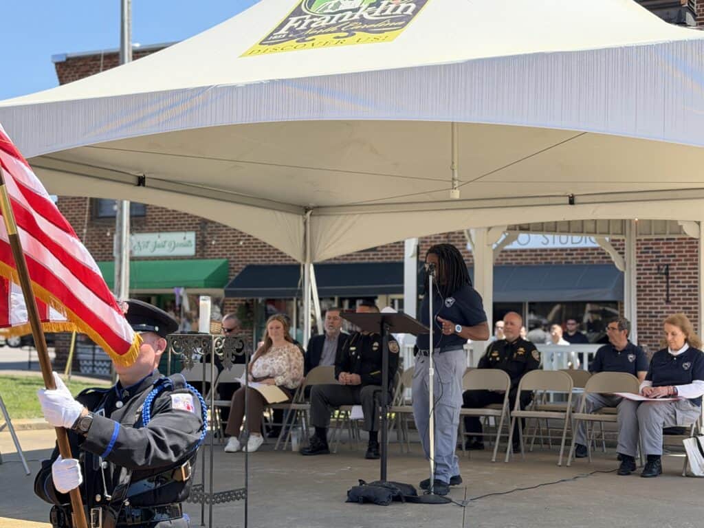 Community gathering at Macon Sense event with speakers and attendees under a tent.