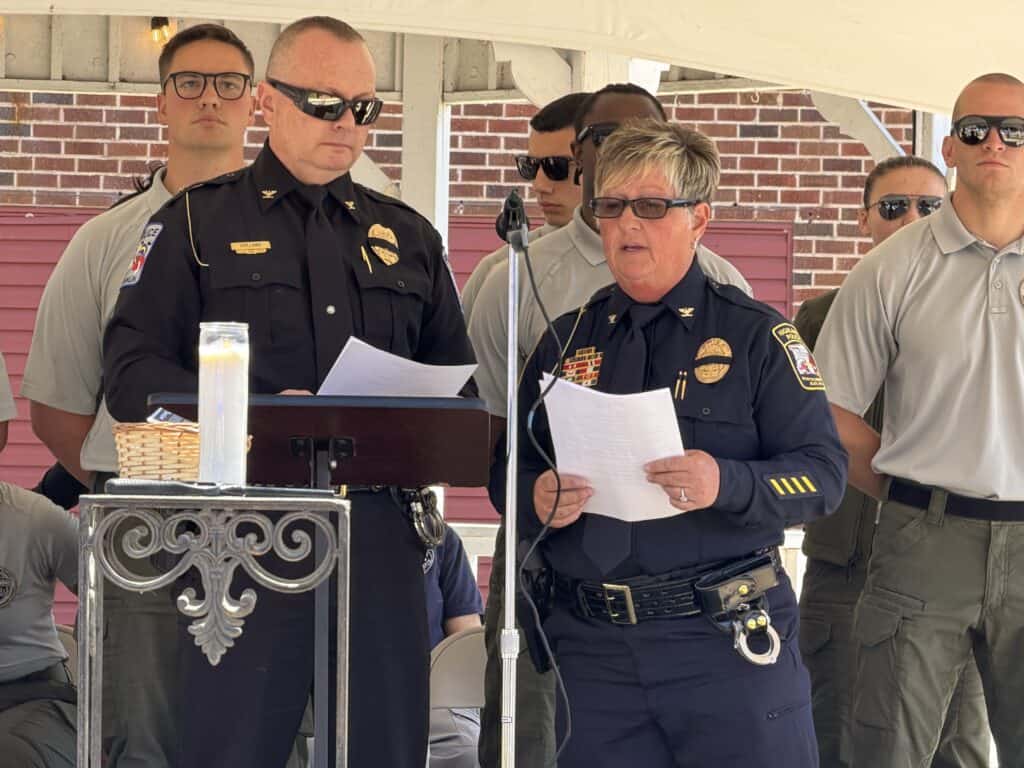 Police officers at a formal ceremony, reading speeches outdoors.