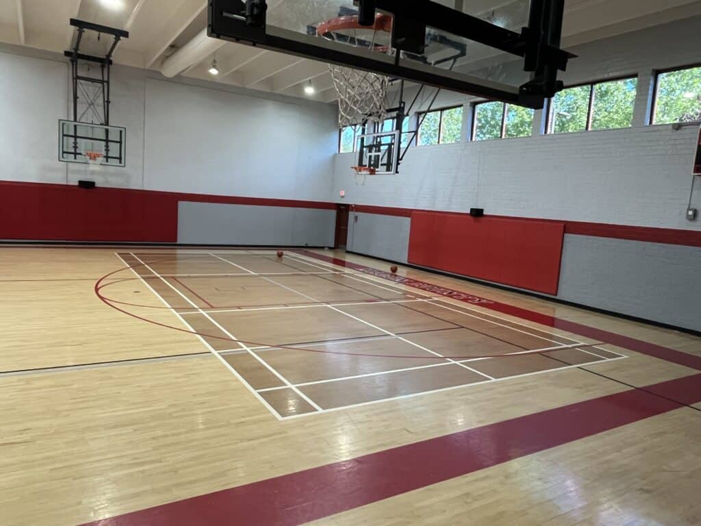 Indoor basketball court with wooden flooring and multiple hoops for sports and training.