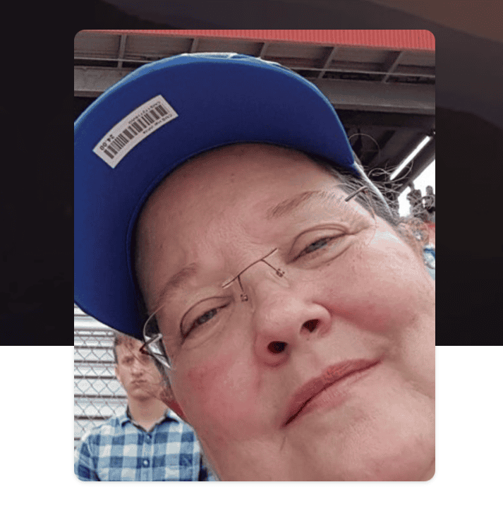 Close-up of Feather Lee Brown Jacobs wearing a blue cap at an event.