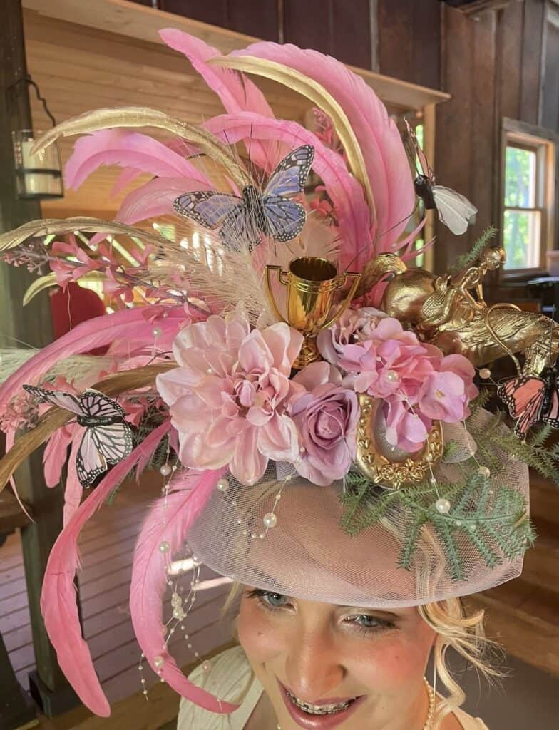 Elegant spring hat featuring pink feathers, butterflies, and floral accents for festive occasions.