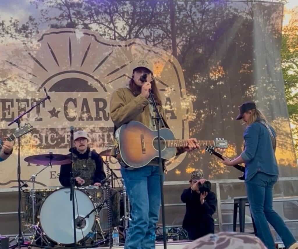 Live band performing at spring festival with trees and sunset in background.