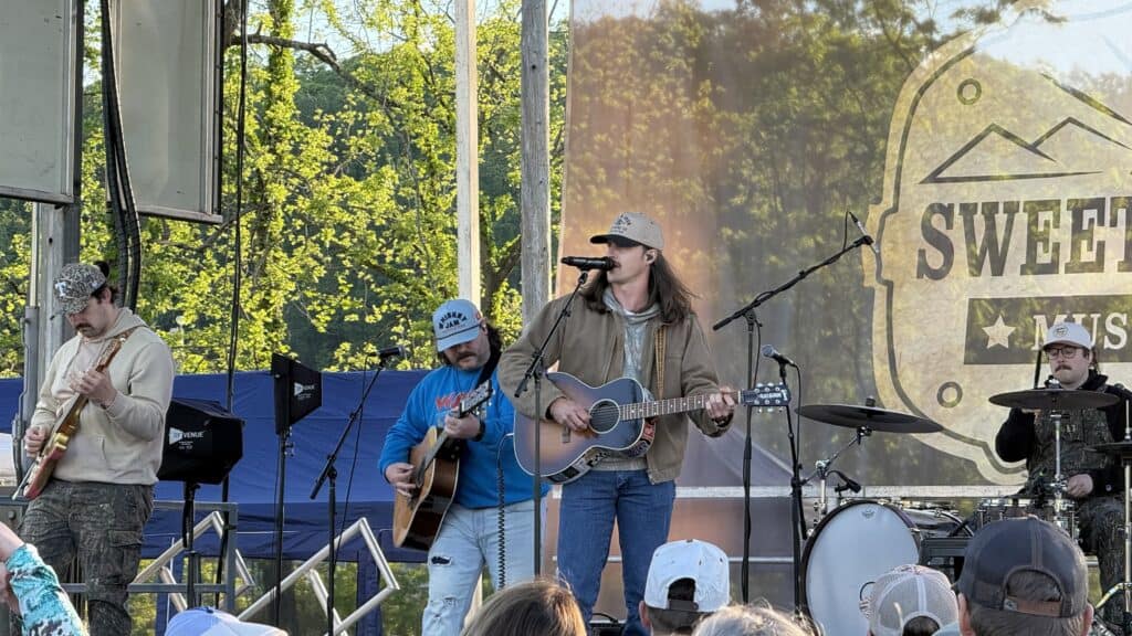 Live band performing at spring festival with trees and crowd in background.