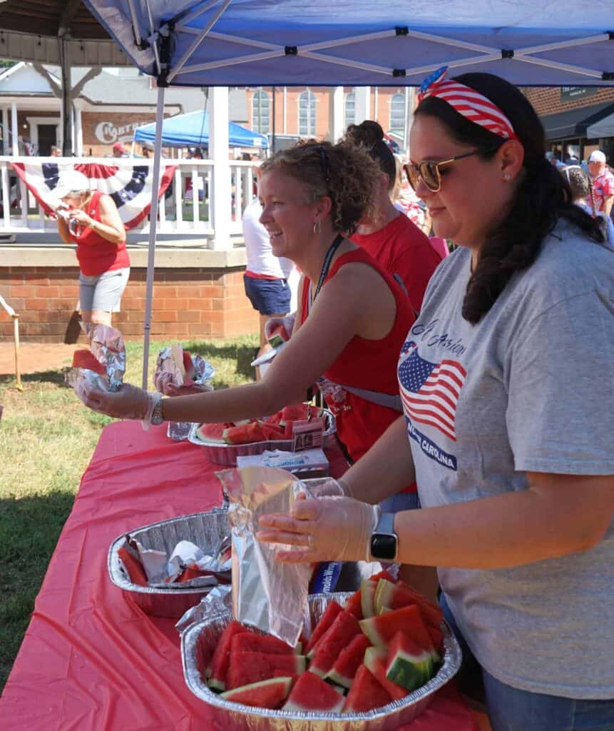 Women serving watermelon at Franklin 4th of July event.
