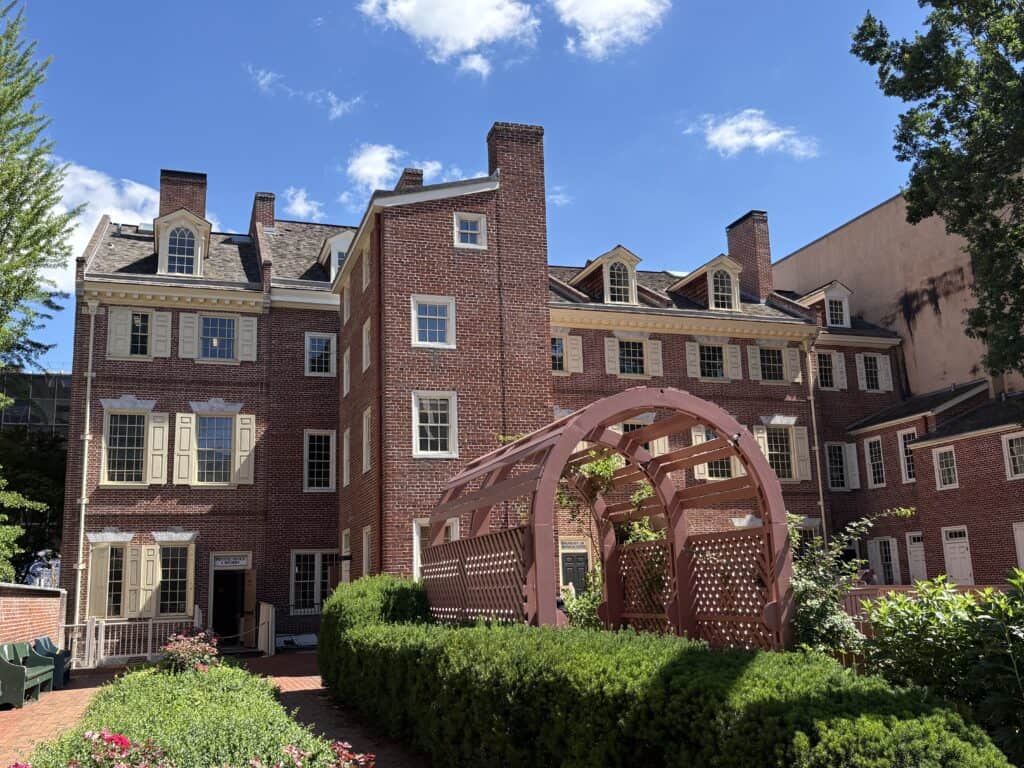 Historic brick apartment building with a pink gazebo in front under a blue sky.