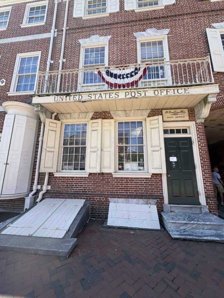 Historic U.S. Post Office with patriotic banner and colonial architecture.