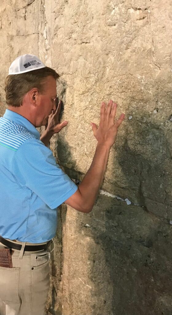 Man inspecting an old stone wall closely, emphasizing historical architecture.
