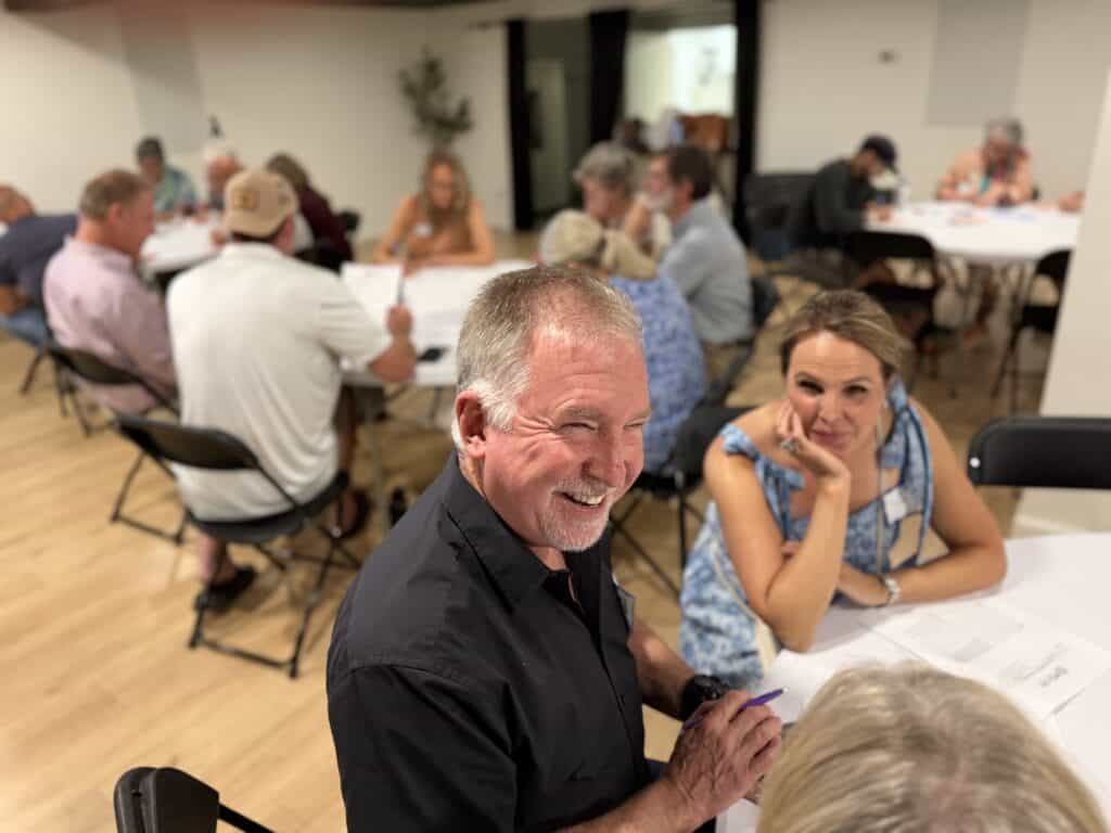 Group of people gathered around tables in a community meeting room.