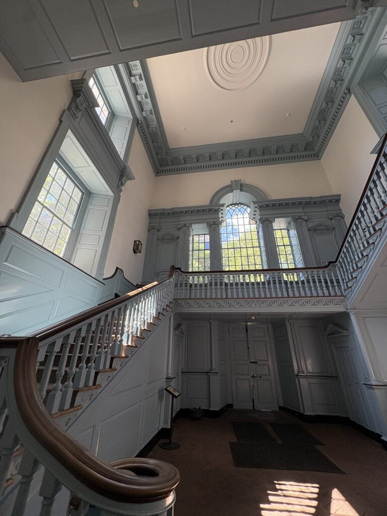 Elegant historic mansion interior with grand staircase and large windows.