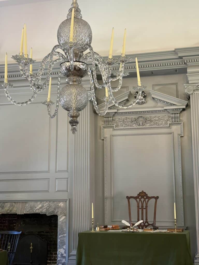 Luxurious crystal chandelier with candles in a historic room setting.
