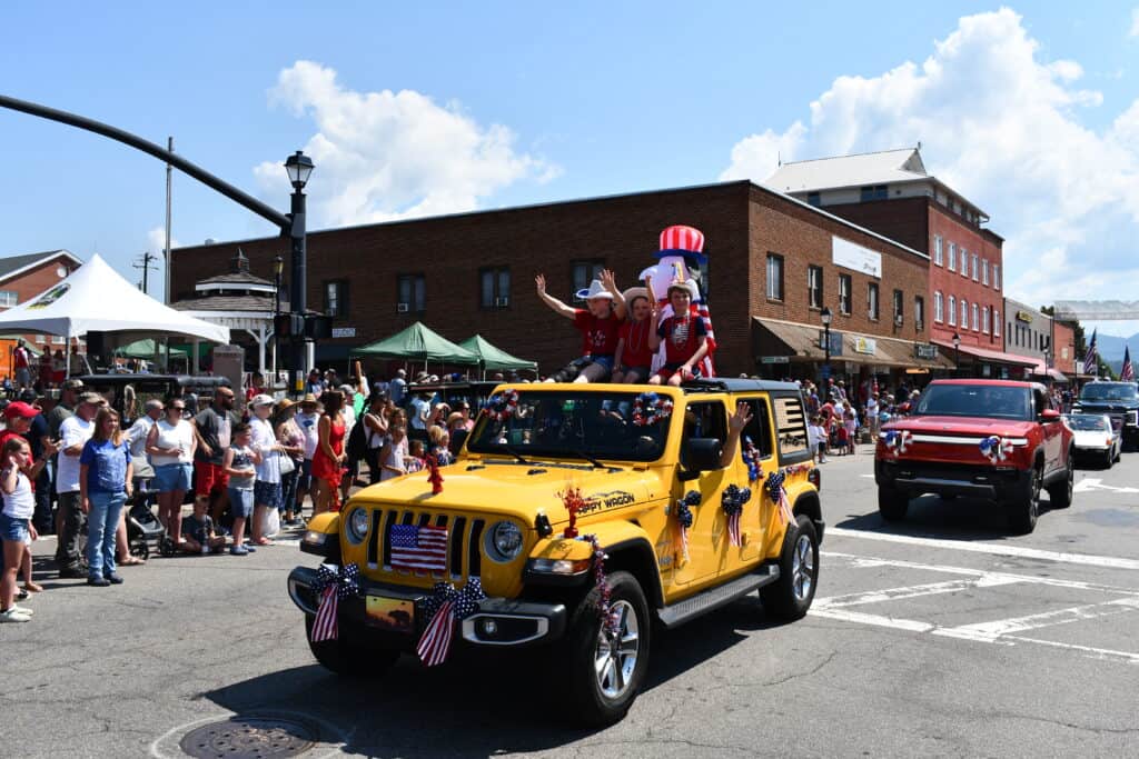 Colorful 4th of July parade with decorated vehicles and crowd in Franklin.