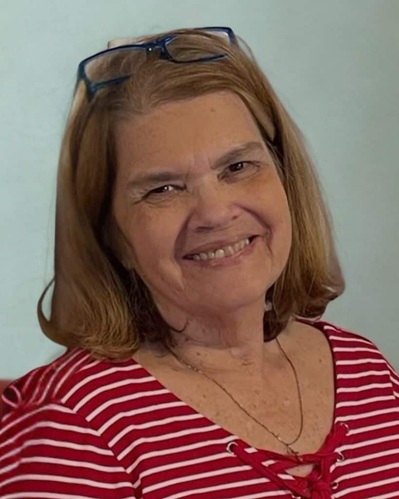Smiling woman with glasses on her head, wearing a red and white striped top.